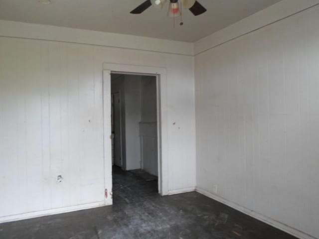 unfurnished room with wood walls and ceiling fan