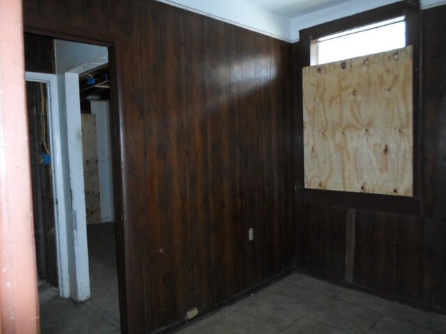 unfurnished room featuring wood walls