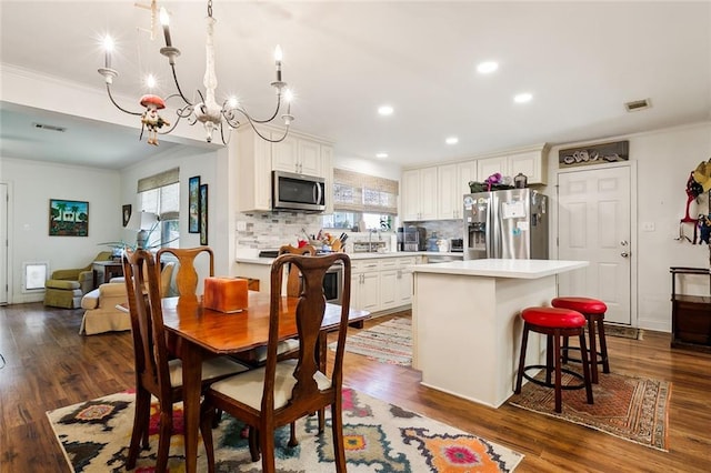 dining room with sink, a chandelier, dark hardwood / wood-style floors, and crown molding