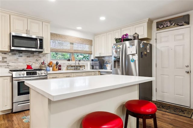 kitchen with dark wood-type flooring, a breakfast bar, backsplash, stainless steel appliances, and sink