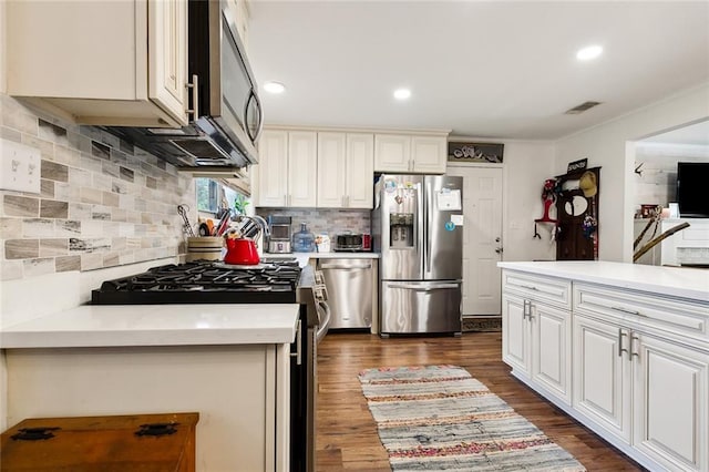 kitchen featuring appliances with stainless steel finishes, decorative backsplash, white cabinetry, and dark hardwood / wood-style floors