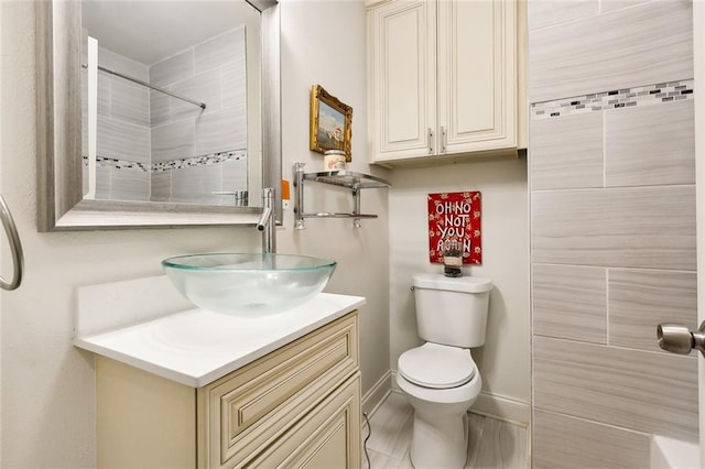 bathroom with a tile shower, vanity, and toilet