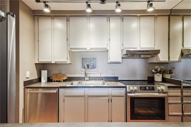 kitchen with stainless steel appliances, sink, white cabinetry, and rail lighting