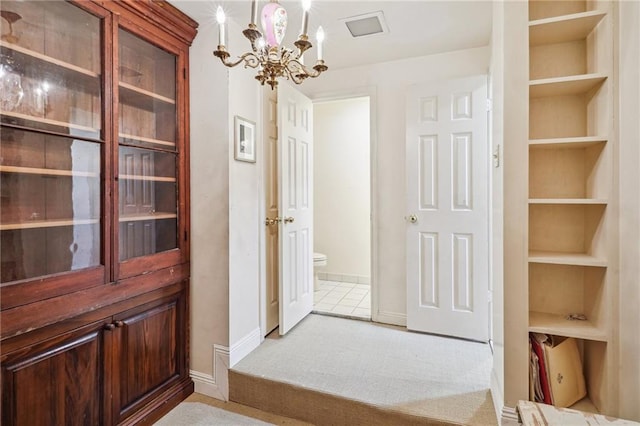 interior space with built in shelves, a chandelier, and light colored carpet