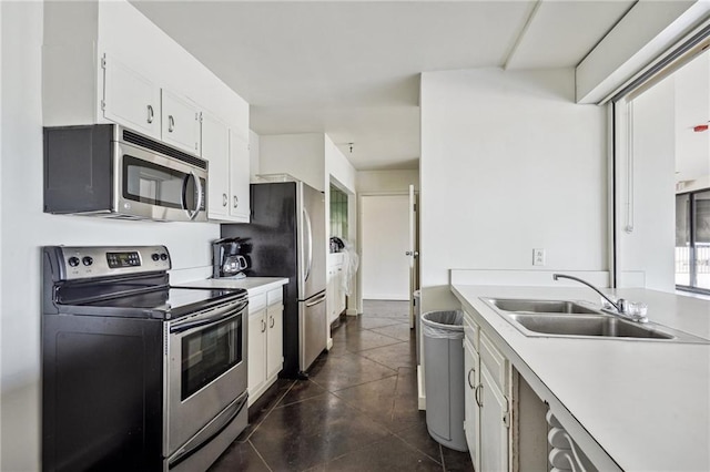 kitchen with dark tile patterned flooring, white cabinets, stainless steel appliances, and sink