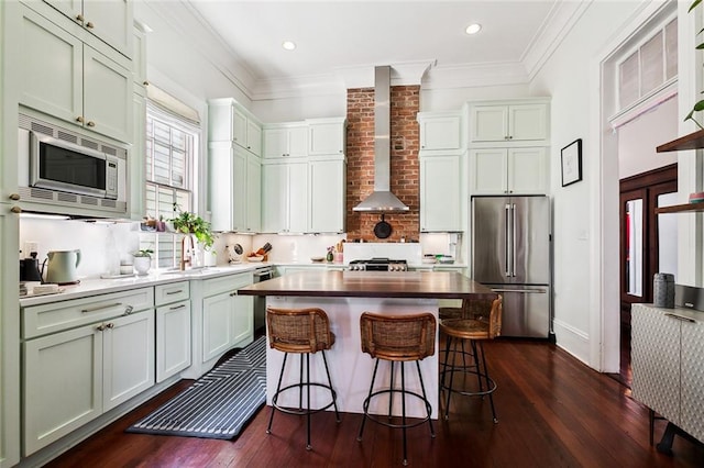 kitchen with wall chimney range hood, a kitchen breakfast bar, stainless steel appliances, dark hardwood / wood-style floors, and a center island