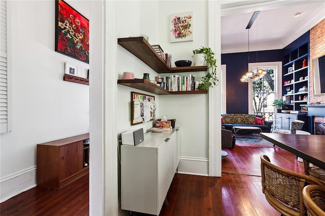 corridor with a notable chandelier, dark hardwood / wood-style floors, and crown molding