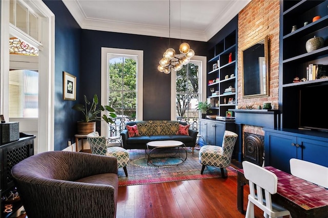 sitting room featuring built in shelves, ornamental molding, dark hardwood / wood-style flooring, and a chandelier