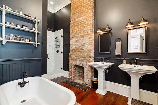 bathroom featuring dual sinks, ornamental molding, independent shower and bath, hardwood / wood-style flooring, and a fireplace