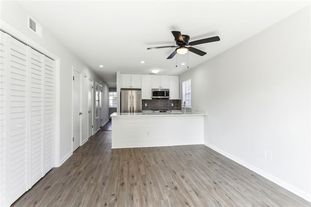 kitchen featuring white cabinets, kitchen peninsula, appliances with stainless steel finishes, and a wealth of natural light