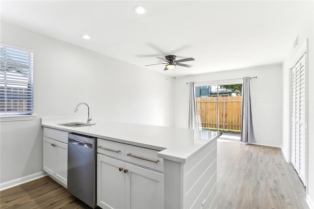 kitchen featuring light hardwood / wood-style floors, sink, white cabinets, kitchen peninsula, and stainless steel dishwasher