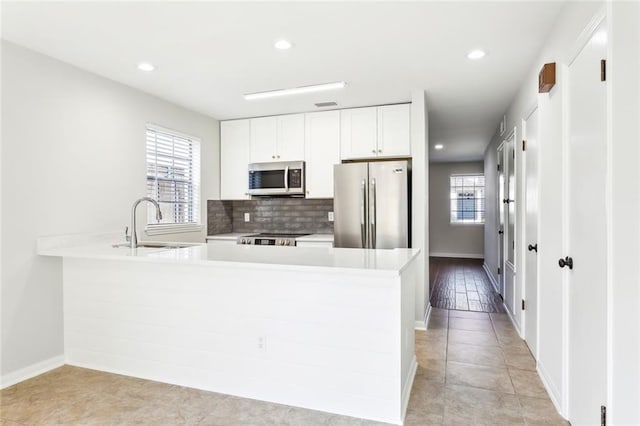 kitchen featuring a healthy amount of sunlight, sink, stainless steel appliances, and white cabinets