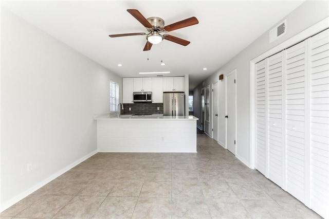 kitchen with ceiling fan, light tile patterned flooring, kitchen peninsula, white cabinetry, and stainless steel appliances