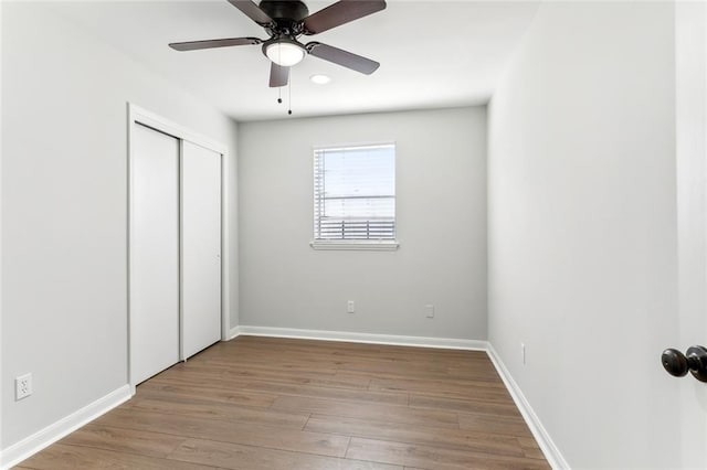 unfurnished bedroom featuring ceiling fan, light wood-type flooring, and a closet