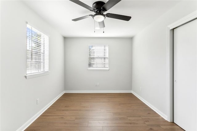 unfurnished bedroom with multiple windows, light wood-type flooring, ceiling fan, and a closet