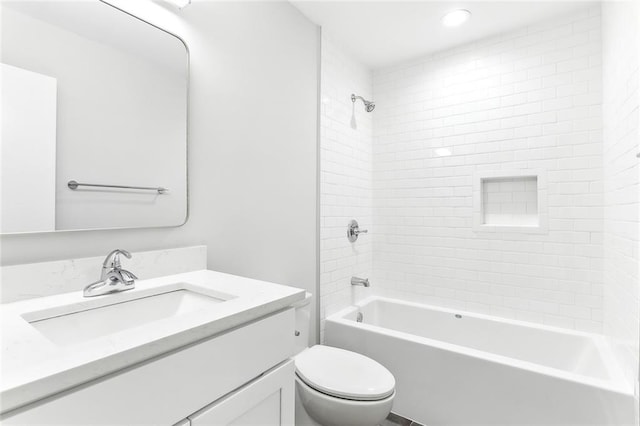 full bathroom featuring tiled shower / bath, vanity, and toilet