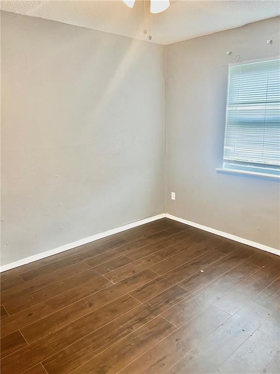 unfurnished room featuring dark wood-type flooring and ceiling fan