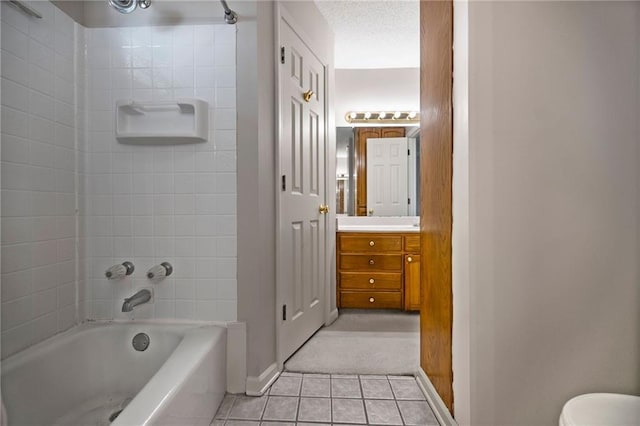 full bathroom with tiled shower / bath, vanity, toilet, a textured ceiling, and tile patterned flooring