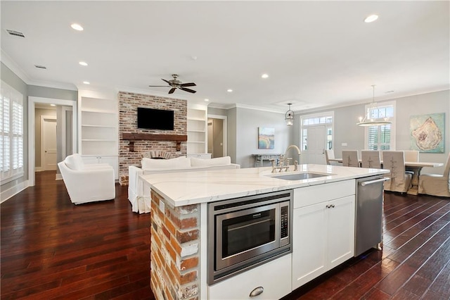 kitchen with a kitchen island with sink, sink, white cabinetry, hanging light fixtures, and stainless steel appliances