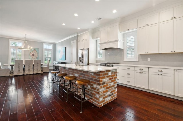 kitchen with appliances with stainless steel finishes, a kitchen island with sink, dark wood-type flooring, and plenty of natural light