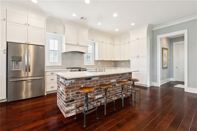 kitchen featuring stainless steel refrigerator with ice dispenser, a kitchen island with sink, and dark hardwood / wood-style floors