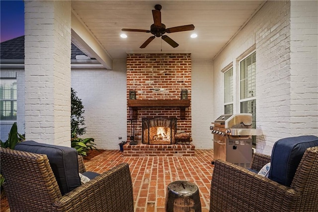 patio terrace at dusk with ceiling fan, an outdoor brick fireplace, and grilling area