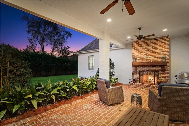 patio terrace at dusk with ceiling fan and an outdoor brick fireplace