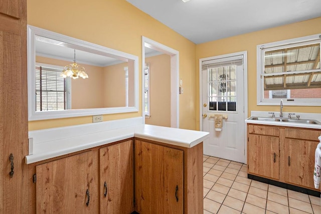 kitchen featuring hanging light fixtures, kitchen peninsula, sink, an inviting chandelier, and crown molding