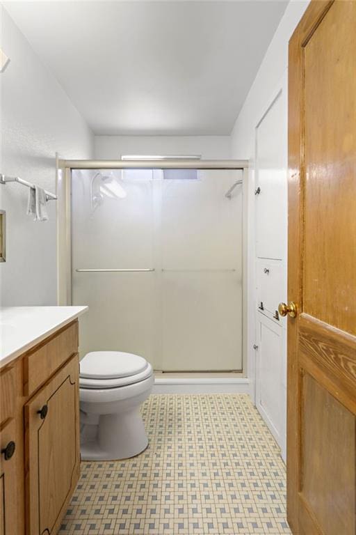 bathroom with a shower with door, vanity, and toilet