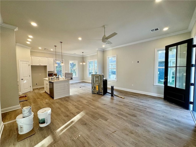 living area with light wood finished floors, crown molding, baseboards, recessed lighting, and a ceiling fan