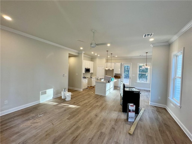 kitchen with visible vents, stainless steel microwave, open floor plan, light wood-style floors, and white cabinetry