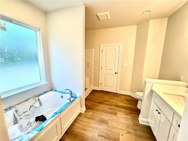 full bathroom with baseboards, toilet, wood finished floors, a bath, and vanity