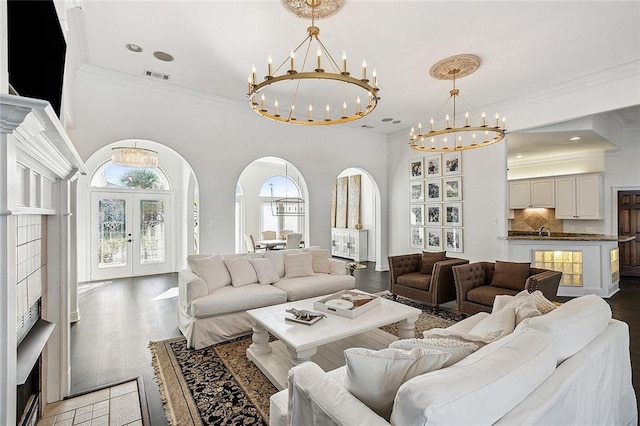 living room with light wood-type flooring, a chandelier, french doors, and crown molding