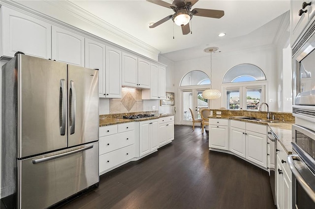 kitchen with stainless steel appliances, white cabinets, dark stone countertops, and sink