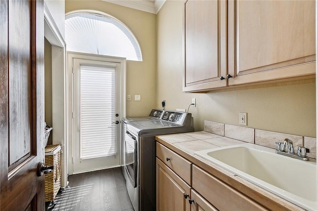 laundry room featuring washing machine and dryer, dark hardwood / wood-style flooring, crown molding, cabinets, and sink