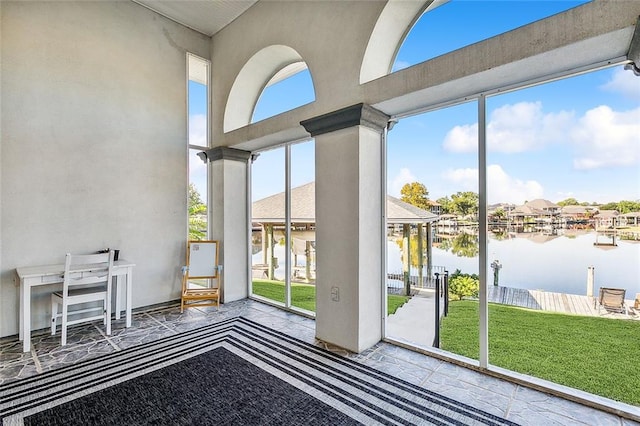 interior space featuring a towering ceiling, a water view, and a healthy amount of sunlight