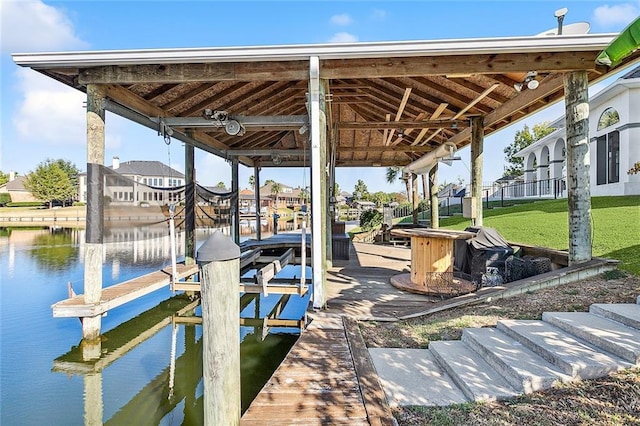 view of dock with a lawn and a water view