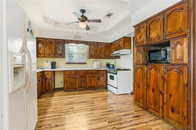 kitchen featuring light hardwood / wood-style floors, ceiling fan, a tray ceiling, and white appliances