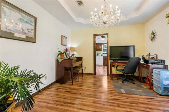 home office featuring hardwood / wood-style floors, a chandelier, and a tray ceiling