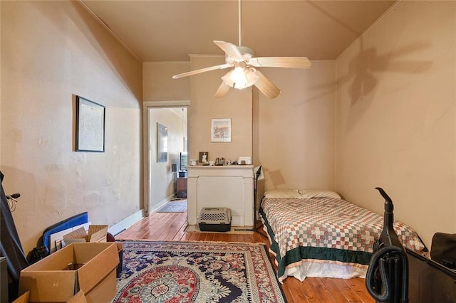 bedroom featuring light wood-type flooring, ornamental molding, and ceiling fan