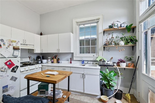 kitchen with white appliances, sink, white cabinets, and a wealth of natural light