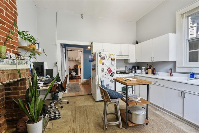 kitchen with a high ceiling, white appliances, and white cabinetry