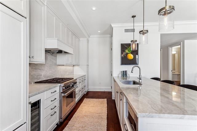 kitchen with hanging light fixtures, high end stainless steel range oven, sink, and white cabinetry