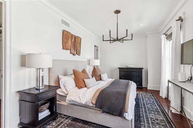 bedroom with ornamental molding, a notable chandelier, and dark wood-type flooring