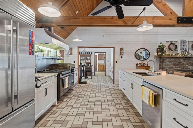 kitchen featuring white cabinetry, high end appliances, wood walls, pendant lighting, and extractor fan