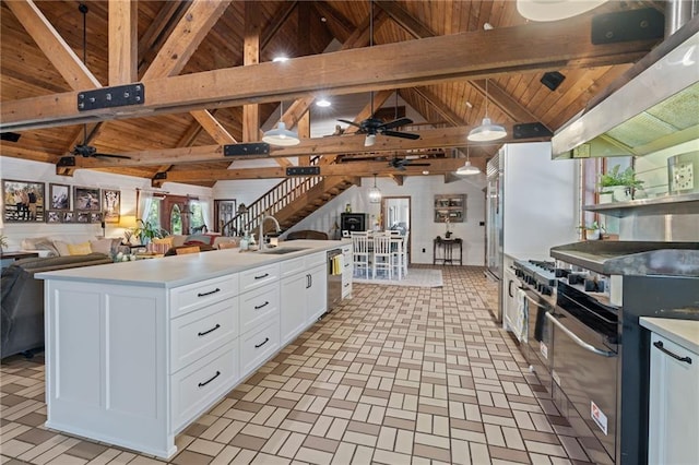 kitchen with ceiling fan, white cabinets, beamed ceiling, sink, and a center island with sink