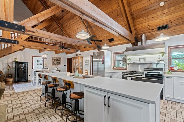 kitchen with stainless steel appliances, white cabinetry, a center island with sink, and decorative light fixtures