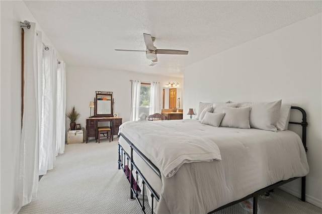 bedroom featuring a textured ceiling, ceiling fan, and light colored carpet