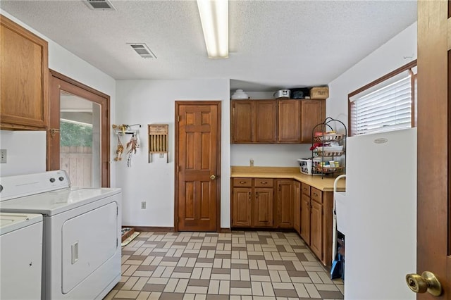 laundry room featuring washer and clothes dryer, cabinets, and a textured ceiling