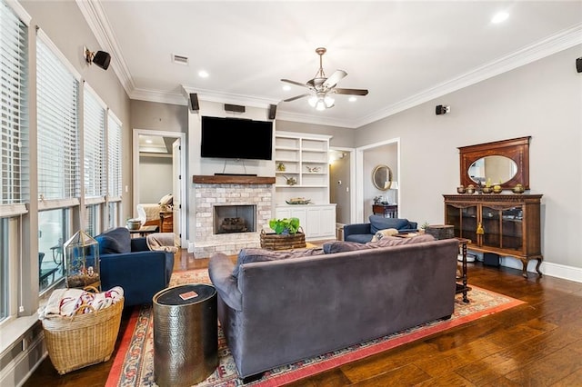 living room with ceiling fan, dark hardwood / wood-style flooring, ornamental molding, and a brick fireplace